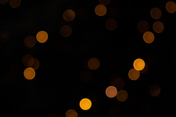 Golden abstract yellow, orange bokeh lights isolated on black background with copy space. Holiday and Christmas season concept, graphic resources, greeting card. wallpaper. Multi-colored lights.