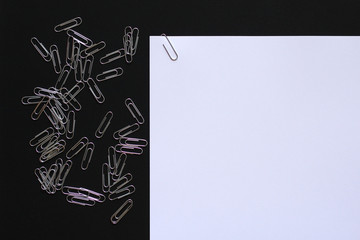 White A4 paper with paper clips spread out on the surface, copy space