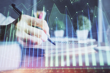 Financial forex charts displayed on woman's hand taking notes background. Concept of research. Double exposure