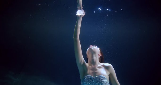 magic fairy is floating underwater and touching surface by hands