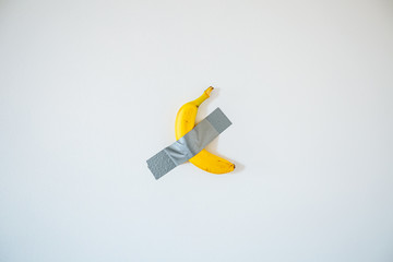 A banana taped to the white wall.