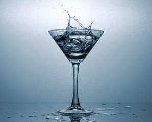A Martini glass with ice and a spectacular splash of the drink.