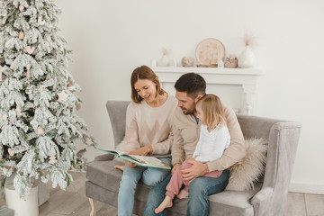 Family Christmas morning in a bright minimalistic living room near the Christmas tree.