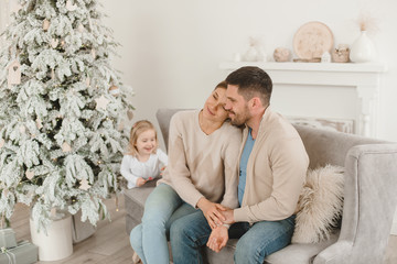 Family Christmas morning in a bright minimalistic living room near the Christmas tree.