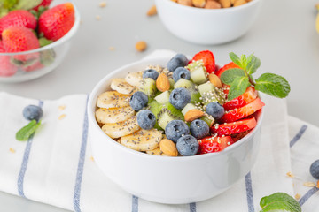 Smoothie bowl with blueberries, banana, strawberries, nuts, kiwi, quinoa, chia and mint. Concept of healthy lifestyle and eating. 