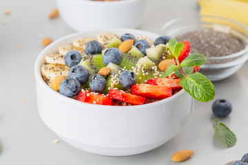 Smoothie bowl with blueberries, banana, strawberries, nuts, kiwi, quinoa, chia and mint. Concept of healthy lifestyle and eating. 