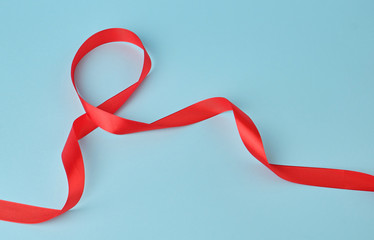 red silk thin ribbon twisted on a blue background