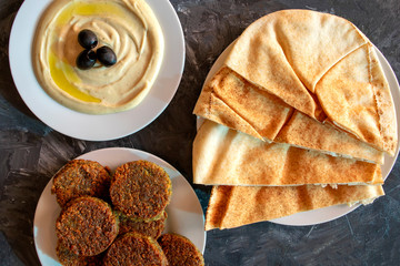 Famous traditional Arabic, Middle East, Israel cuisine. Tahini sauce, pita bread and falafel on gray background. Flat lay, top view. 