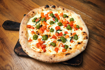 Freshly baked pizza with cheese, sauce and vegetables on a wooden table