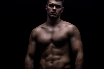Fototapeta na wymiar sexy muscular bodybuilder with bare torso isolated on black
