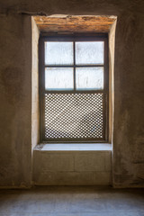 Single Interleaved grunge wooden ornate window - Mashrabiya - in stone wall at abandoned building