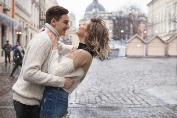 Fototapeta premium A couple in love in the city under the snow laughing and looking at each other