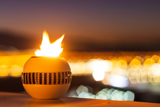 Amazing View Of The City  Lights And Mountains At Sunset Through A Decorated Candle Light. Bright Fire In A Romantic Restaurant.