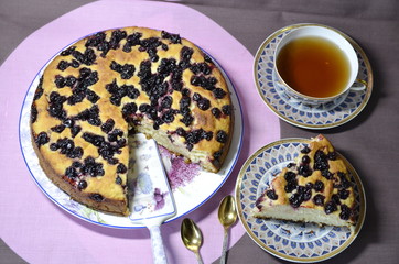 Homemade baking. On the table is a dish with a freshly baked delicious blackcurrant pie, a cup of tea.