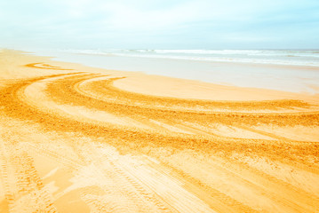Fototapeta premium Circular tyre prints on beautiful sandy Pismo beach, Pacific Ocean Coast. The only state park in California, USA, where cars are allowed on the beach. Abstract car adventure summer fun background.