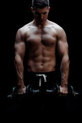 Fototapeta na wymiar sexy muscular bodybuilder with bare torso excising with dumbbells isolated on black