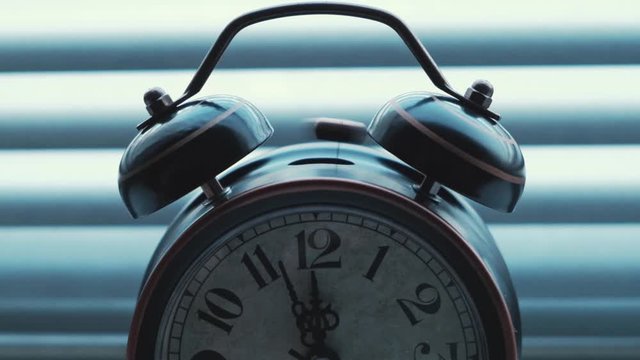 An old vintage alarm clock chimes at twelve o'clock.