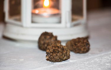 Christmas and New Year's background with candles, fir cones and beads on an old wooden table in rustic style, toned image.