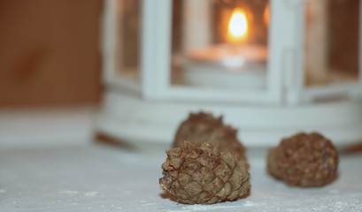 Christmas and New Year's background with candles, fir cones and beads on an old wooden table in rustic style, toned image.