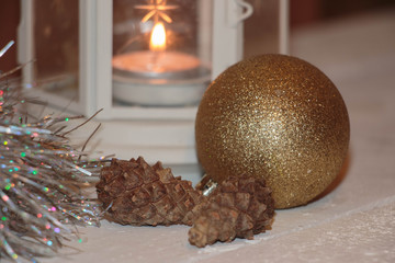 Christmas and New Year's background with candles, fir cones and beads on an old wooden table in rustic style, toned image.