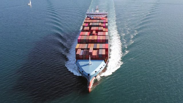 Large loaded Container Ship roaring across the open sea, Aerial view.