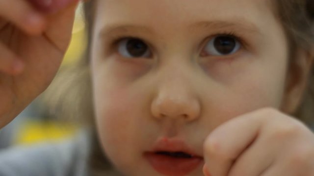Child mouth bites rose donut. Closeup baby girl eating doughnut with glase. Delicious, sweet, sweettooth