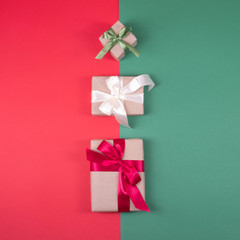 Obraz premium Beautiful packaging of presents with satin ribbons, craft paper on red and green background.