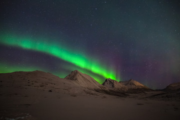 Dramatic polar lights, Aurora borealis over the mountains in the North of Europe - Tromso, Norway.long shutter speed.