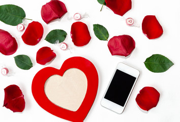 beautiful heart-shaped frame with a phone and red rose petals