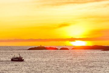 fishing boat with amazing sunset in background in lofoten, norway.