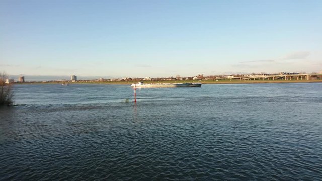 Coastal trading vessel crossing the river on a clear day.