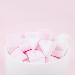Cup of pink marshmallow hearts on a pale pink background. Valentines day love concept. Copy space