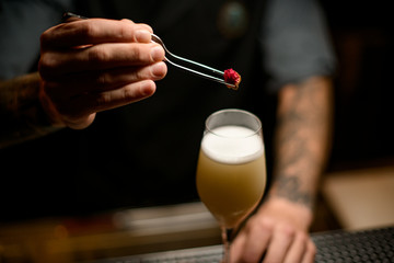 Professional bartender decorated the yellow creamy color alcoholic cocktail drink with a little rose bud