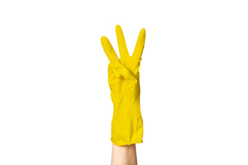 A female hand in a yellow rubber glove for cleaning shows a gesture on a white isolated background. Three fingers