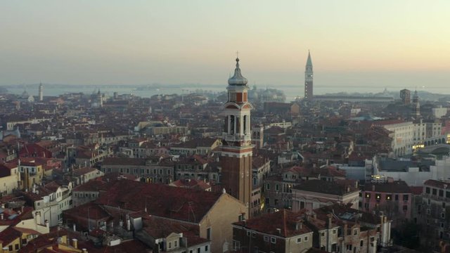 Aerial, tracking, drone shot towards the Chiesa Cattolica Parrocchiale dei Santi Apostoli, on a sunny evening, in Venice city, Italy