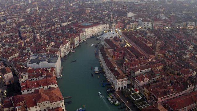 Aerial, reverse, drone shot tilting up above the grand canal, revealing the cityscape of Venezia, on a sunny evening, in Venice city, Italy