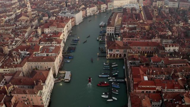 Aerial, tilt, drone shot overlooking boats and gondolas on the Canalaso, the canal grande di Venezia, on a sunny evening, in Venice city, Italy