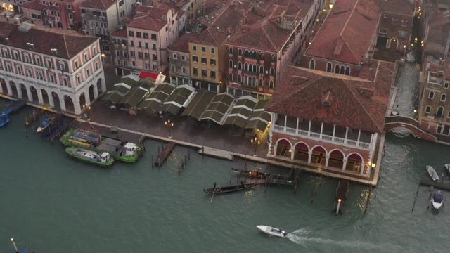 Aerial, pan, drone shot following a white boats passing gondolas on the Canalaso, the canal grande di Venezia, on a sunny evening, in Venice city, Italy