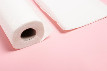 Roll of paper towels and few pieces towels on a pink background. Concept is 100 natural product, delicate and soft. Flat lay, top view. Banner