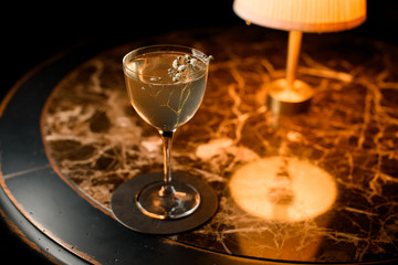 Murky transparent alcoholic cocktail drink decorated with a twig with flowers