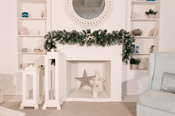 Christmas tree and a chair stands near the fireplace  and other holiday decorations in white loft