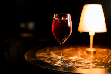 Transparent red color alcoholic cocktail drink with an ice in the glass