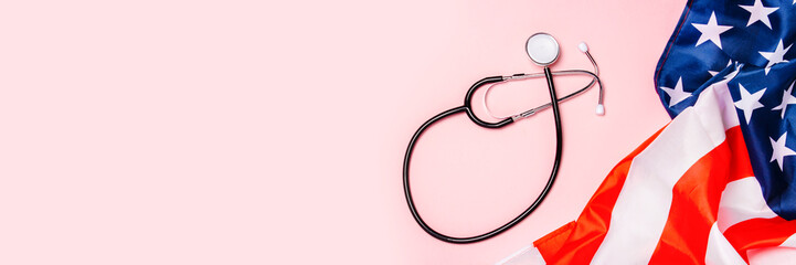 Medical stethoscope and US flag on a pink background. Concept of health care, medicine, virus,...