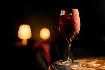 Transparent red alcoholic cocktail drink with an ice in the glass