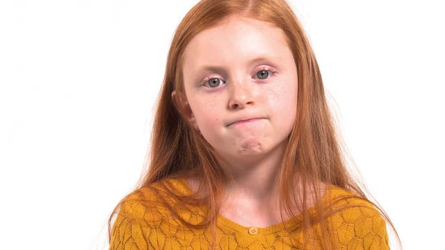 Close-up portrait shot of a lovely child with long foxy hair at loss. Schoolgirl does not know what to answer. True emotions concept