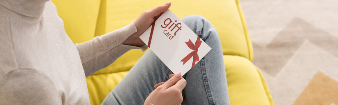 Cropped View Of Young Woman Holding Gift Card On Sofa, Panoramic Shot