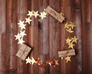 Party Mockup Round Gold Stars Frame on Dark Wood. Christmas Shiny Golden Tinsel and Gifts. Card Design with Copy Space