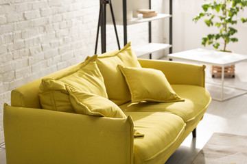 Comfortable yellow sofa with sunlight in living room