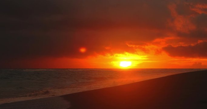 Tropical beach. Dark orange clouds day to night sky reflected in big waves crushing coast. Beautiful dramatic sunset sky. Red purple orange blue pink sunset cloud background. Ocean surfer lifestyle.