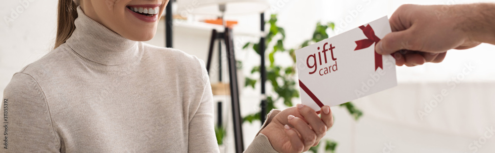 Wall mural Cropped view of man giving gift card to smiling woman